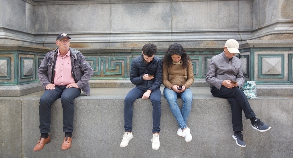 Un grupo de personas leen el móvil en Viena (Austria). / CRHISTOPHER BURGUESS