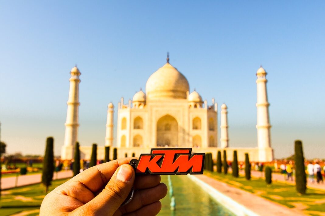 Un viajero sostiene en la mano un llavero de goma de color naranja de KTM en Uttar Pradesh con el Taj Mahal, una de las siete maravillas del Mundo, al fondo. FOTOGRAFÍA: ULTIMATE TRAVEL PHOTOS