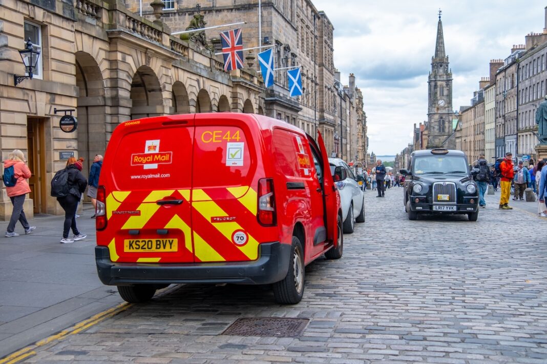 Una furgoneta del servicio postal británico con un taxi típico inglés, en este caso un 'black cab' eléctrico, en una calle de Edimburgo, en Reino Unido. FOTOGRAFÍA KITTY FLY